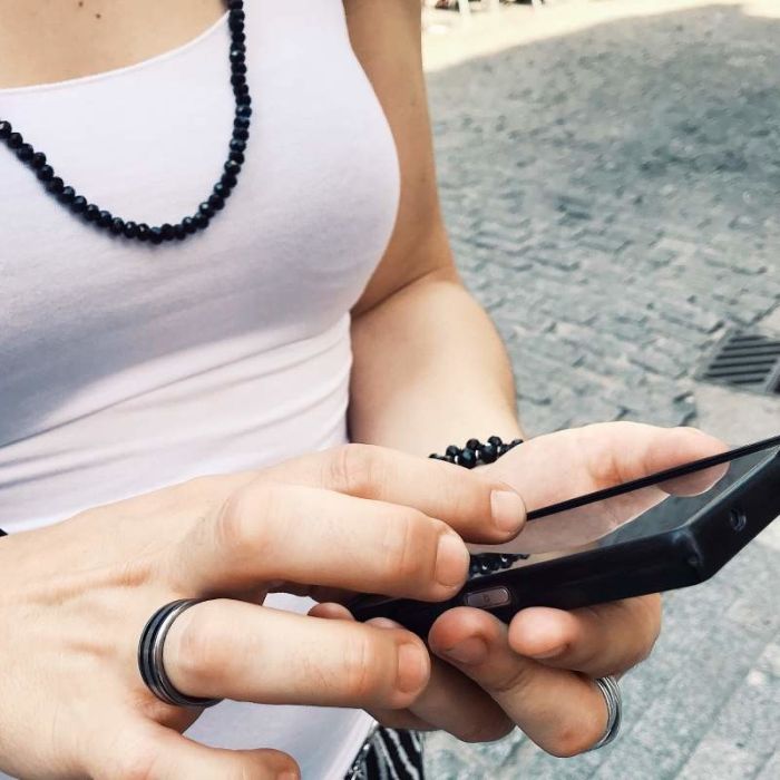 Performance Analyse von Instagram im Vergleich zu TikTok. Junge Frau nutzt ihr Handy auf der Straße.